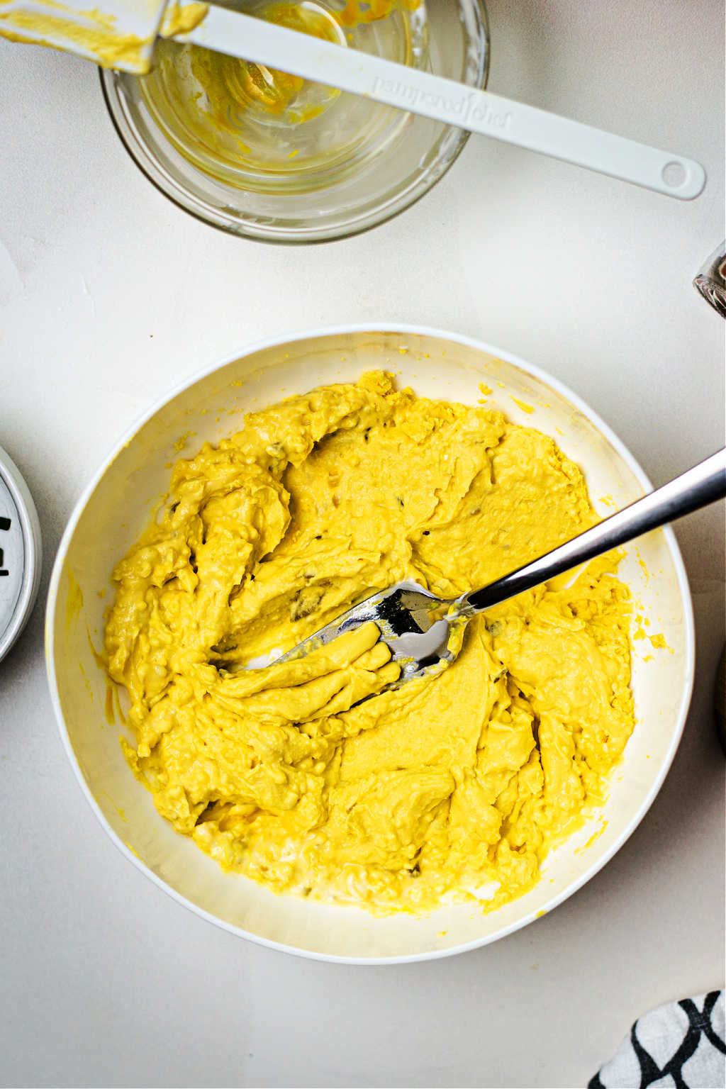 egg yolk mixture in a white bowl with a fork for filling southern deviled eggs.