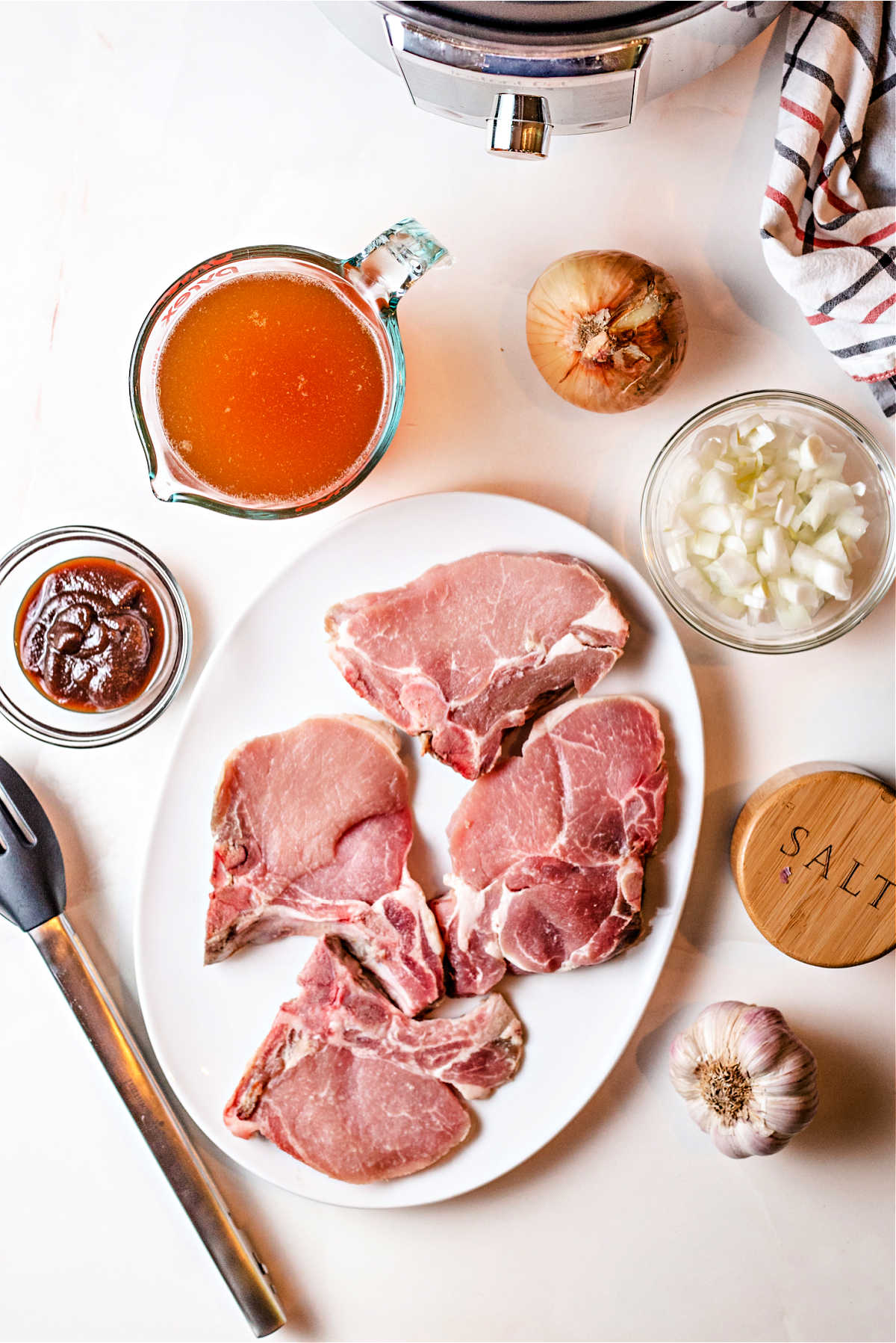 ingredients for instant pot pork chops on a counter: pork chops, apple butter, chicken broth, onion, and garlic.