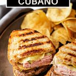 Sandwich Cubano on a grey plate with potato chips.