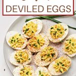 deviled eggs on a white plate garnished with paprika and freshly snipped chives.