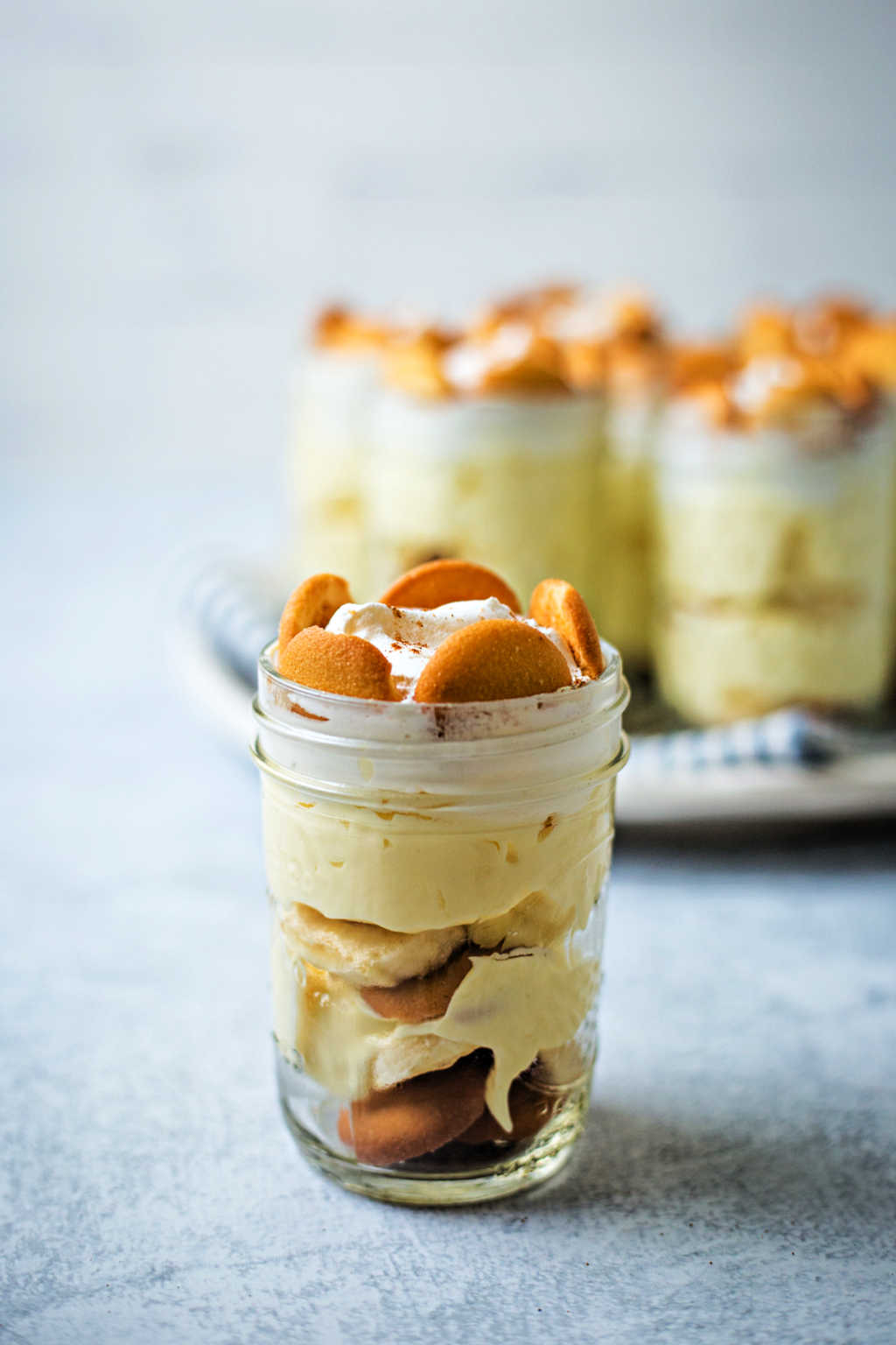 no bake banana pudding in small mason jars on a table.