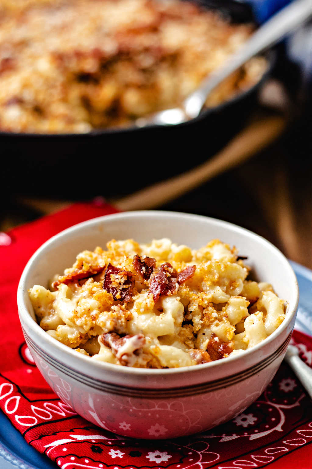 a bowl of smoked mac and cheese on top of a red bandana on a wooden table.