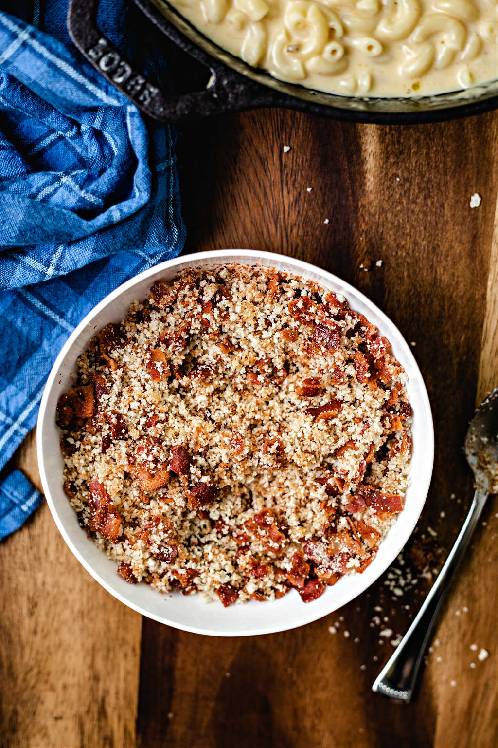 a bowl of bacon and panko crumb topping for smoked mac and cheese on a wooden table.