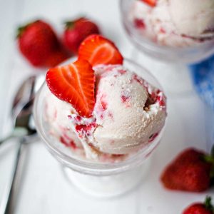 a bowl of homemade strawberry ice cream on a table.