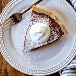 CHOCOLATE CHESS PIE ON A WHITE PLATE WITH A DOLLOP OF WHIPPED CREAM.
