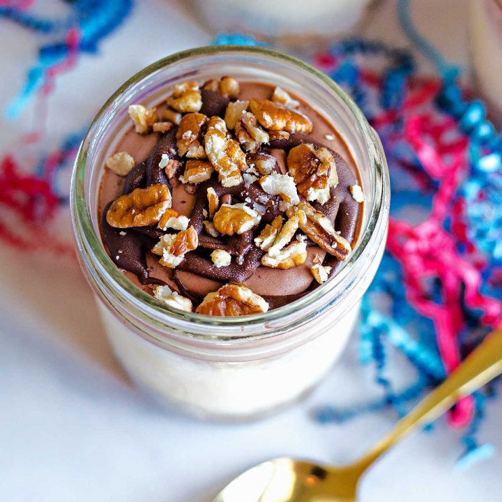 ice cream pie in a jar with chocolate whipped cream, nutella, and nuts.