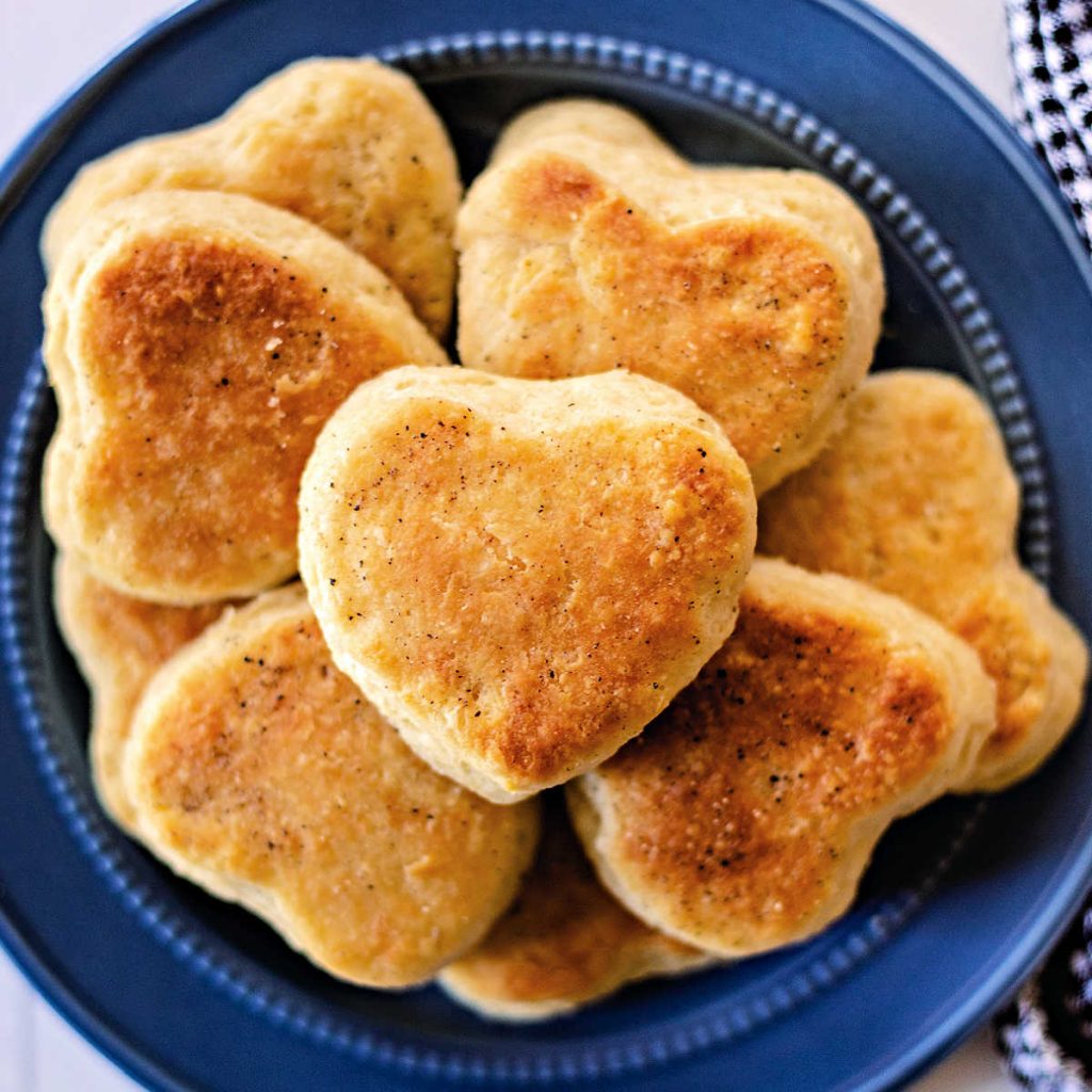 biscuits cut in heart shapes piled on a blue plate.