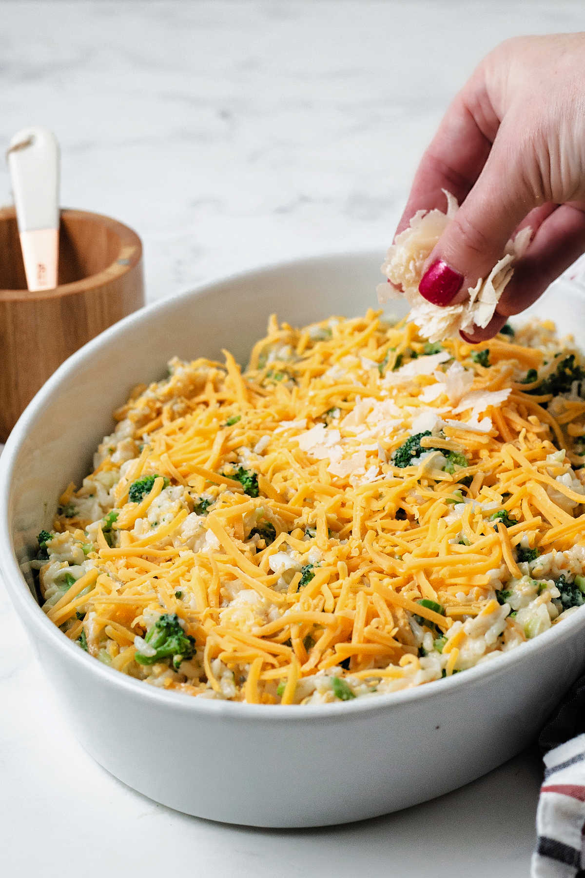 sprinkling shaved parmesan cheese on an unbaked casserole.