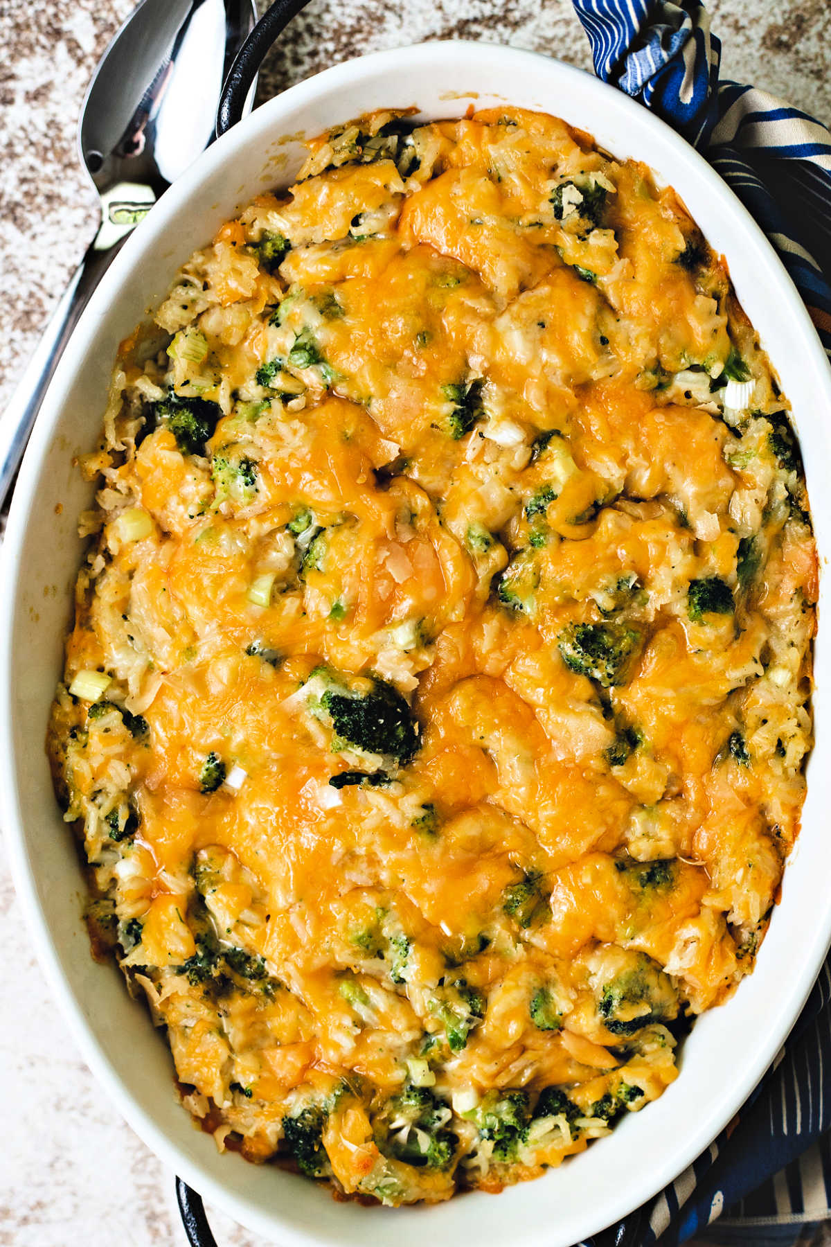 broccoli rice and cheese casserole in a white oval dish on a table.