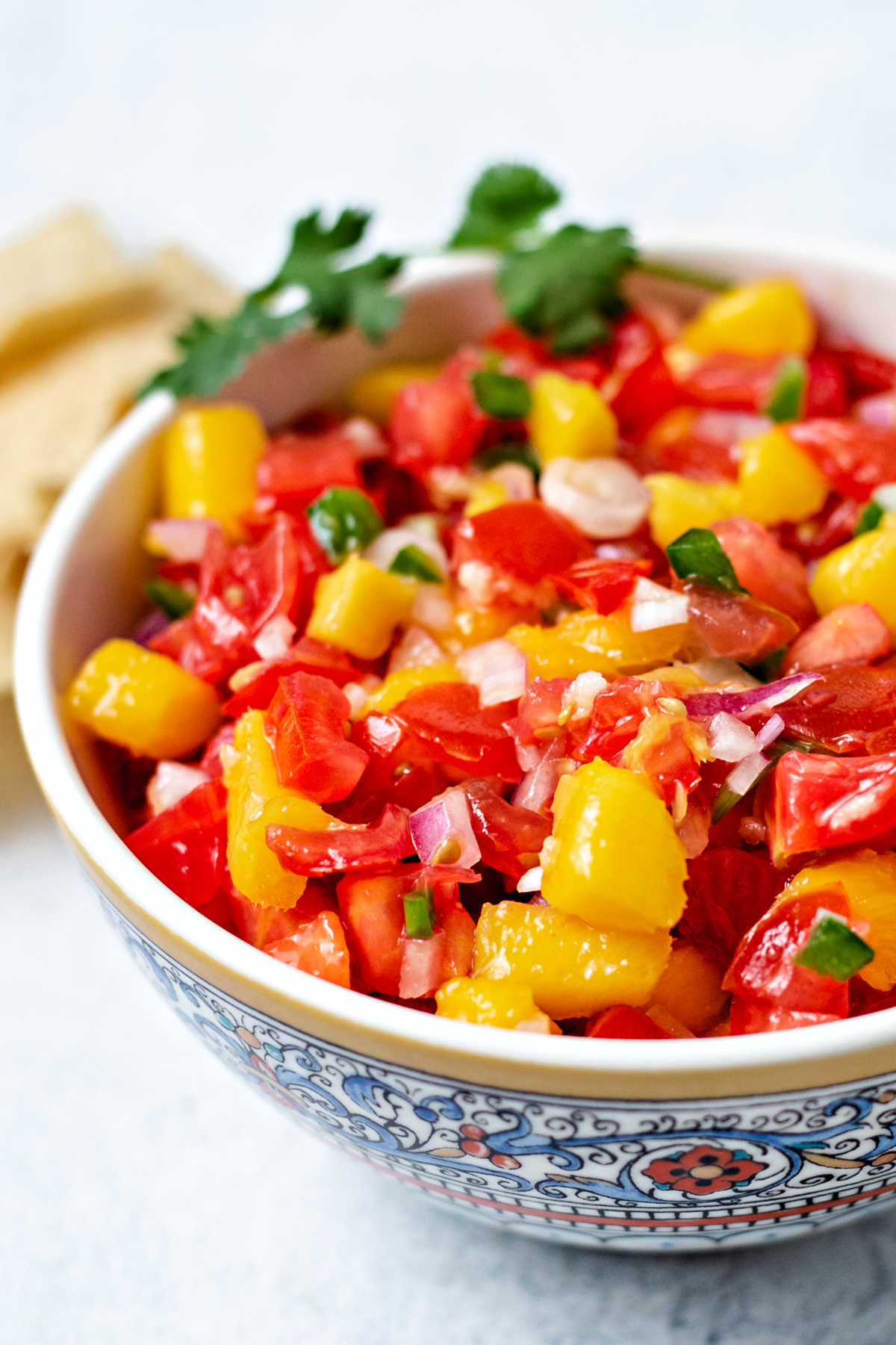 close up image of mango tomato salsa in a bowl on a table.