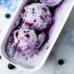 a container of blueberry ice cream with an old fashioned ice cream scoop.