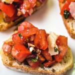 a slice of bruschetta with tomato salad on a white plate.