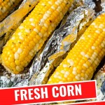 an ear of grilled corn with holders in each end on a crumpled piece of aluminum foil on a blue plate.
