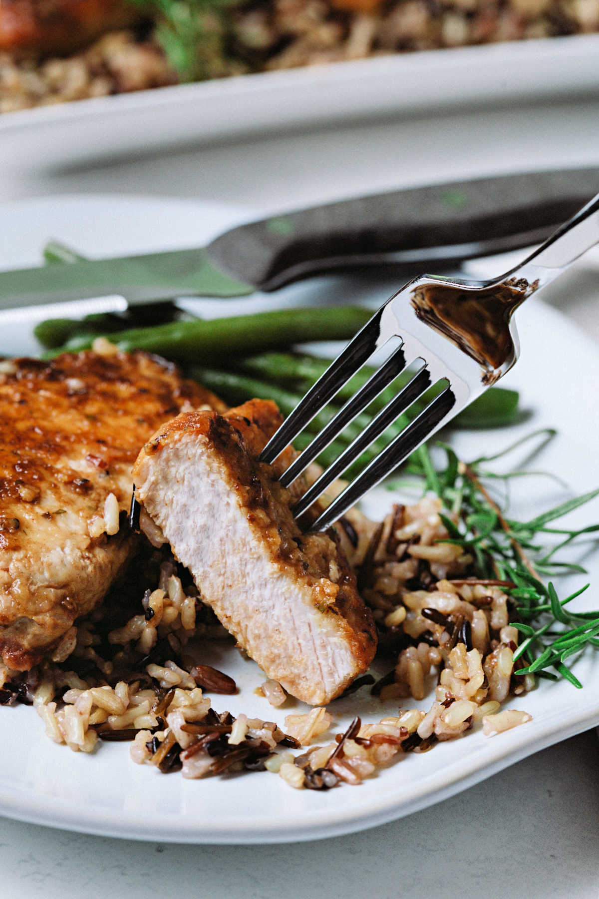 a fork speared into a cut piece of balsamic pork chop;