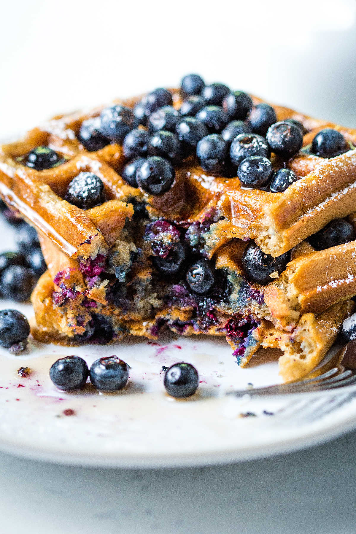 a stack of partially eaten blueberry waffles on a plate.