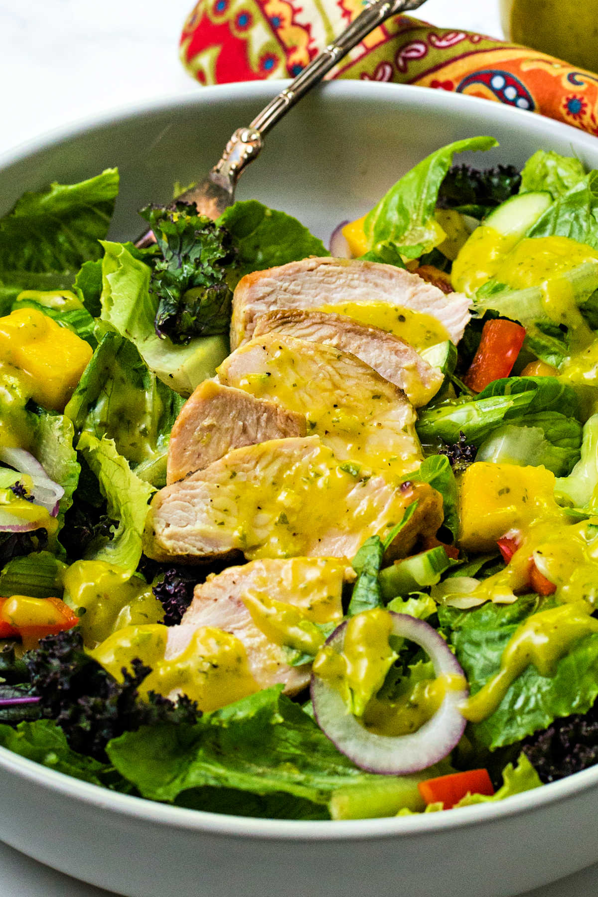 close up image of a chopped salad with slices of grilled chicken dressed with mango dressing.