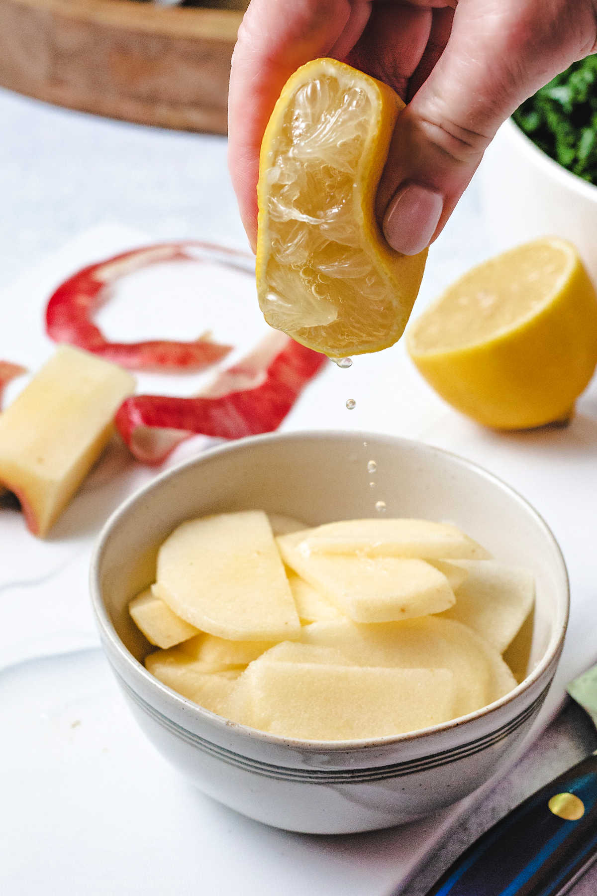 squeezing a fresh lemon into a bowl of apple slices.