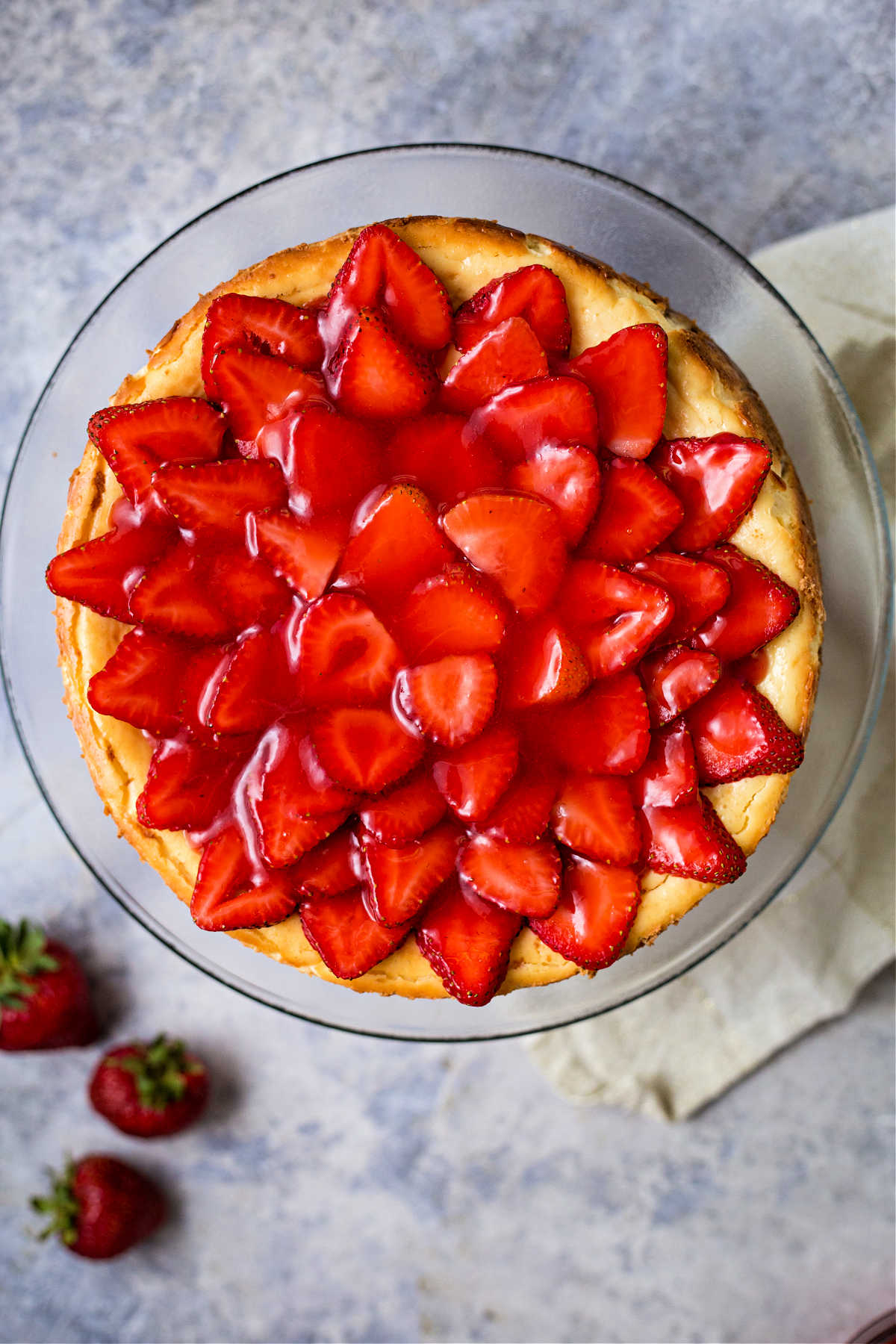 whole uncut strawberry cheesecake on a cake plate.