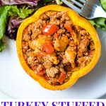 a yellow bell pepper stuffed with saucy turkey mixture on a plate with a side salad.