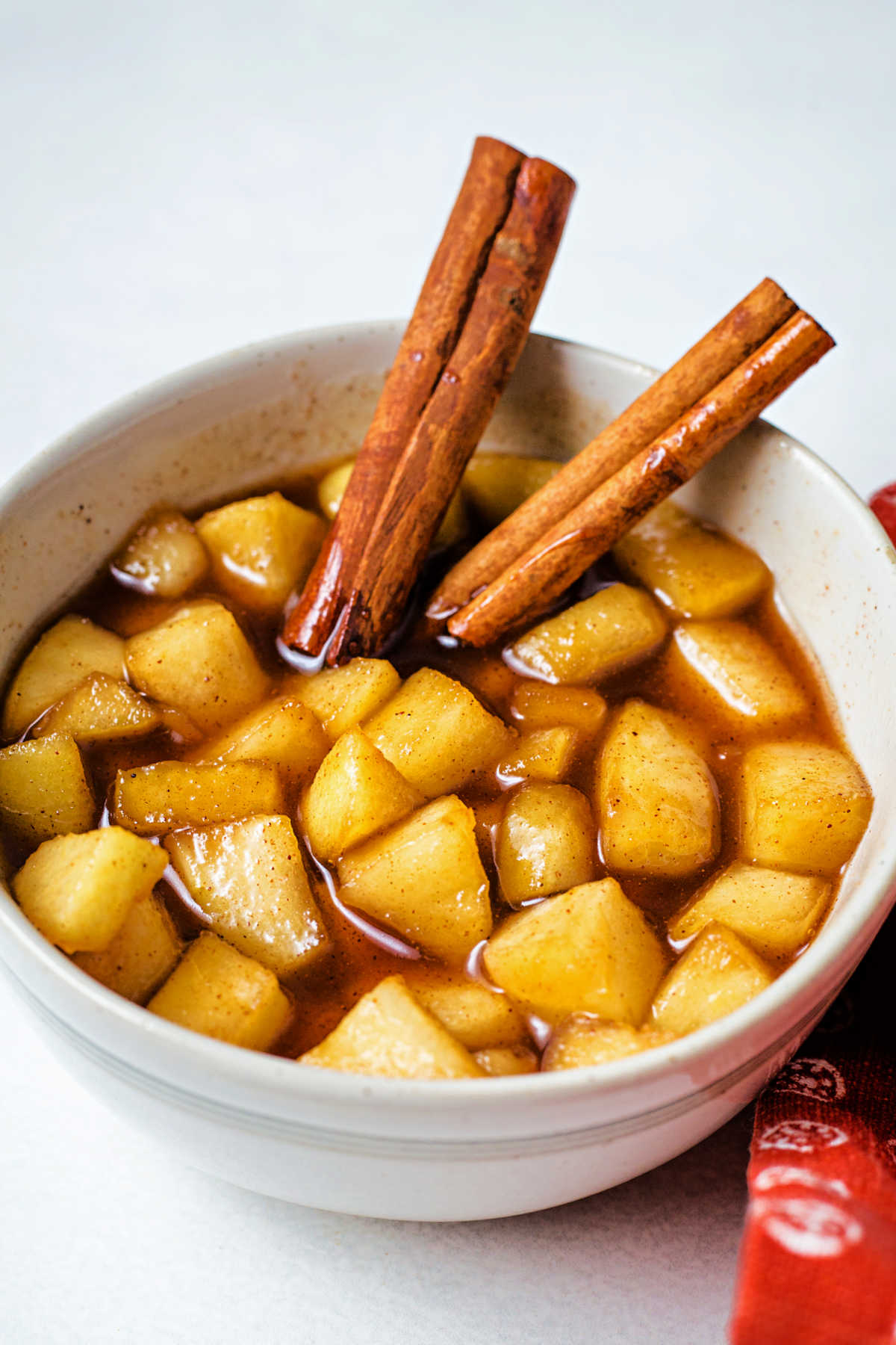 a bowl of apple compote with cinnamon sticks.