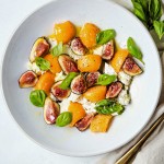 fig salad with fresh mozzarella and cantaloupe in a shallow white bowl on a table.