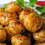 side view of a plate of chicken meatballs garnished with parsley on top of a red napkin on a table.