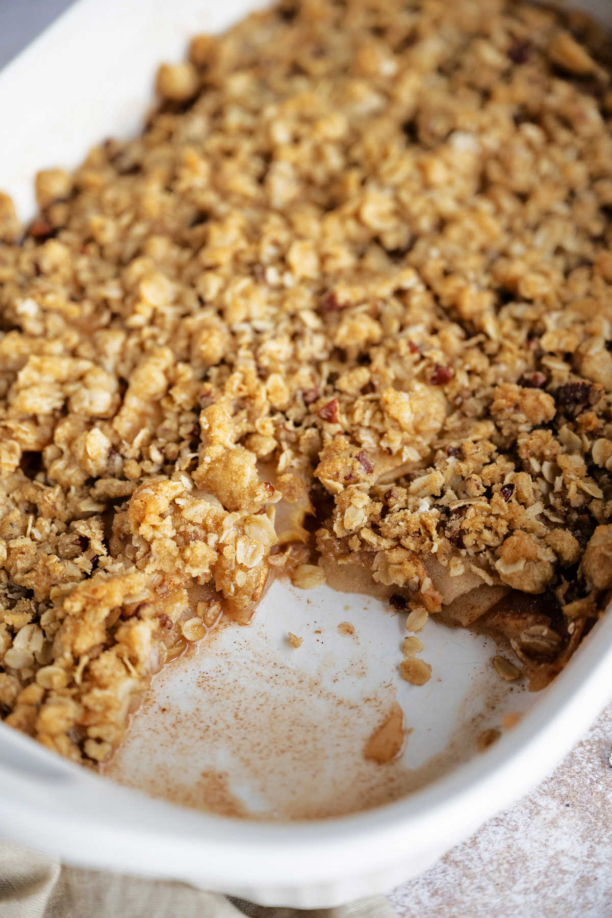 apple crisp in a baking dish with a serving missing in the corner.