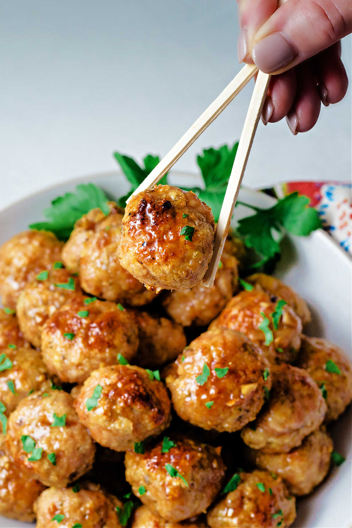 holding a chicken meatball with chopsticks.