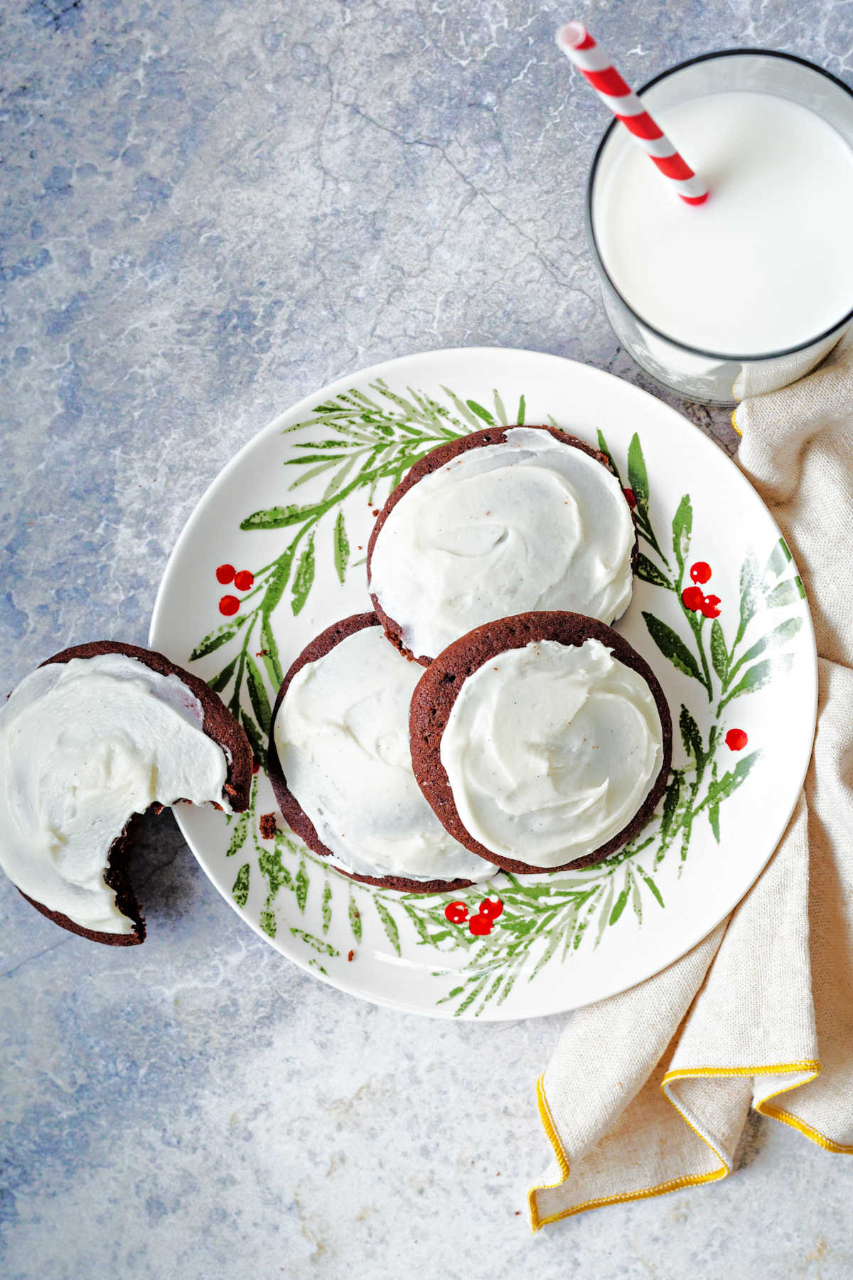 frosted chocolate drop cookies on a holiday plate with a glass of milk in the background.