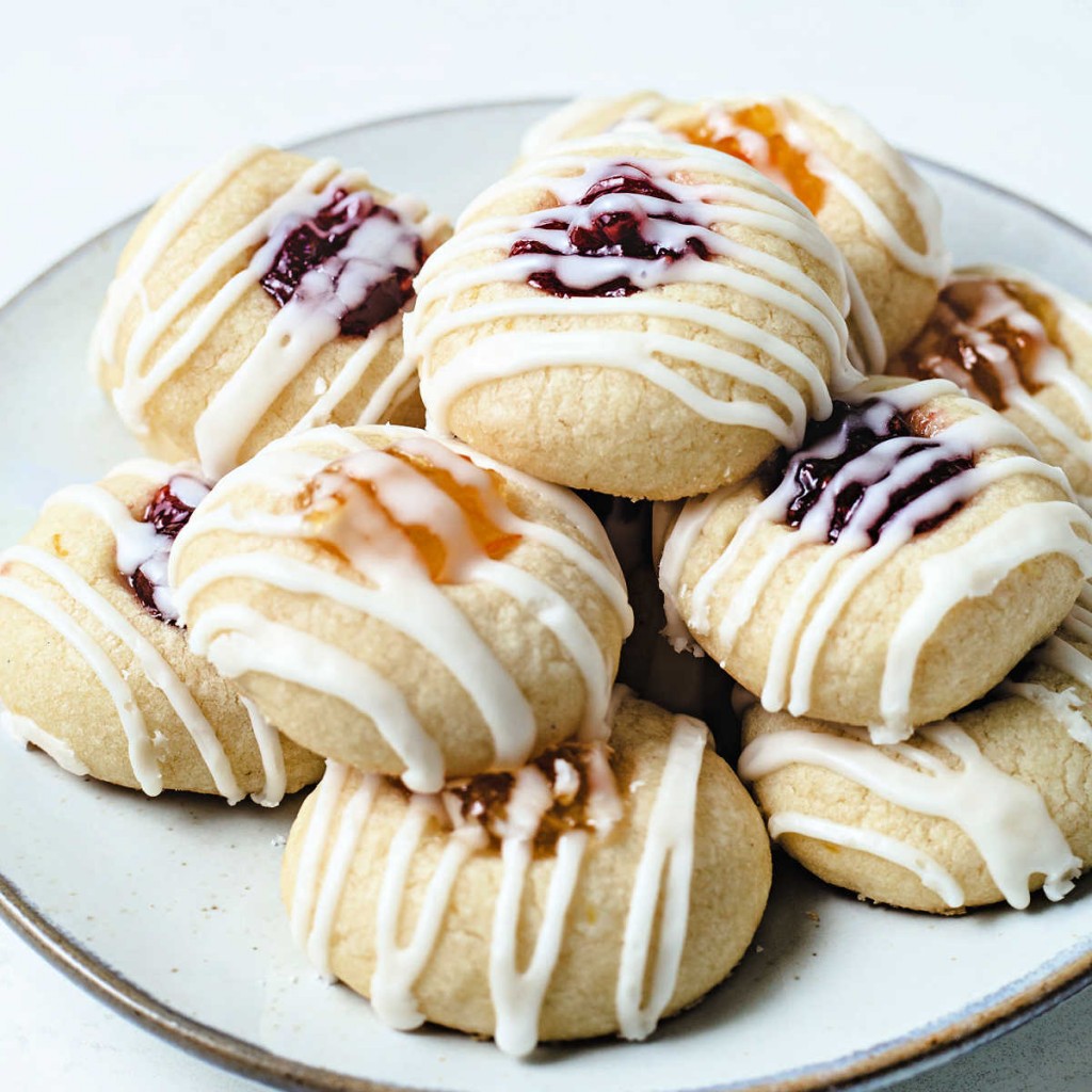 a plate of jam thumbprint lemon short bread cookies with raspberry and orange marmalade filling..