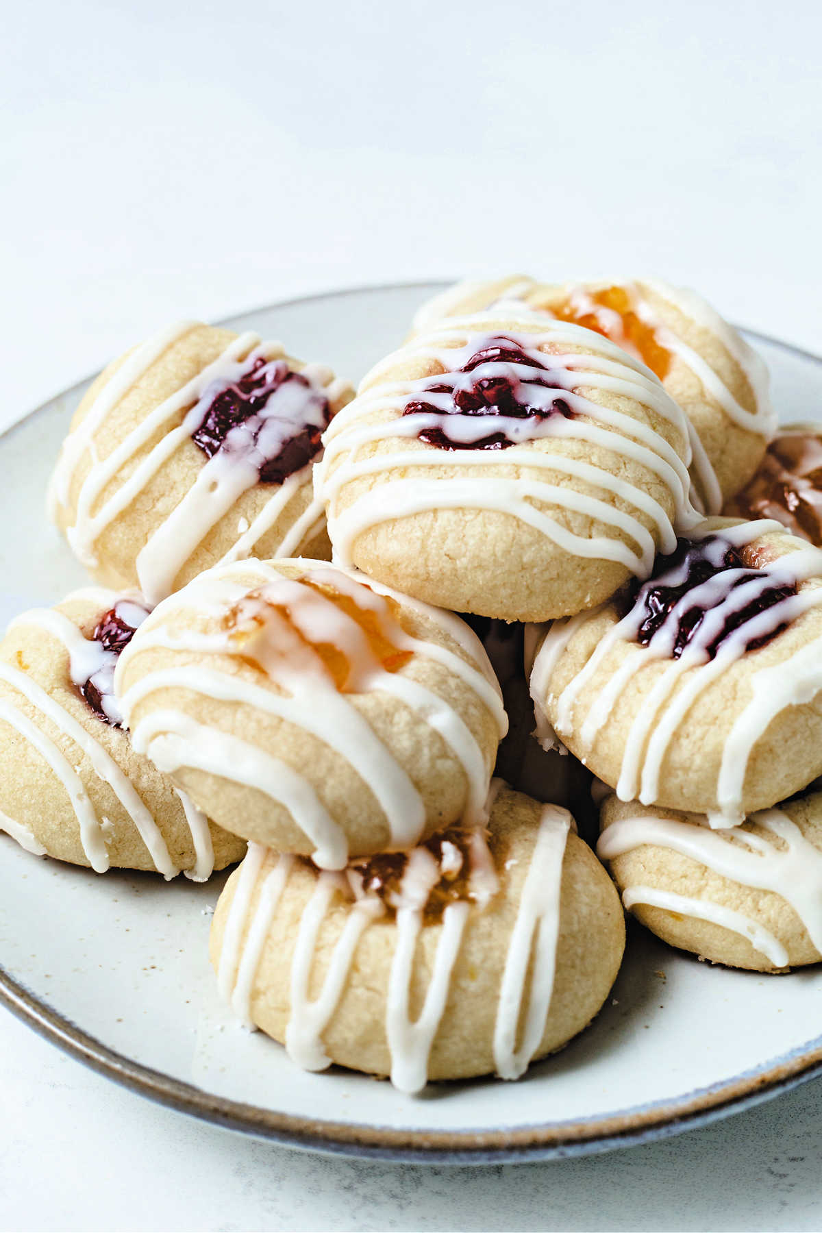 a plate of jam thumbprint lemon short bread cookies with raspberry and orange marmalade filling..