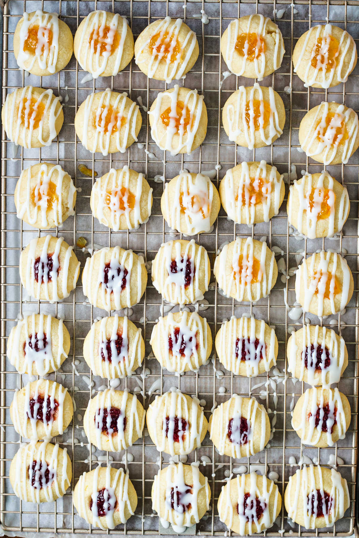 jam thumbprint cookies on a wire rack drizzled with glaze.