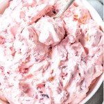 a bowl of cranberry fluff with a serving spoon nestled into the fluff.