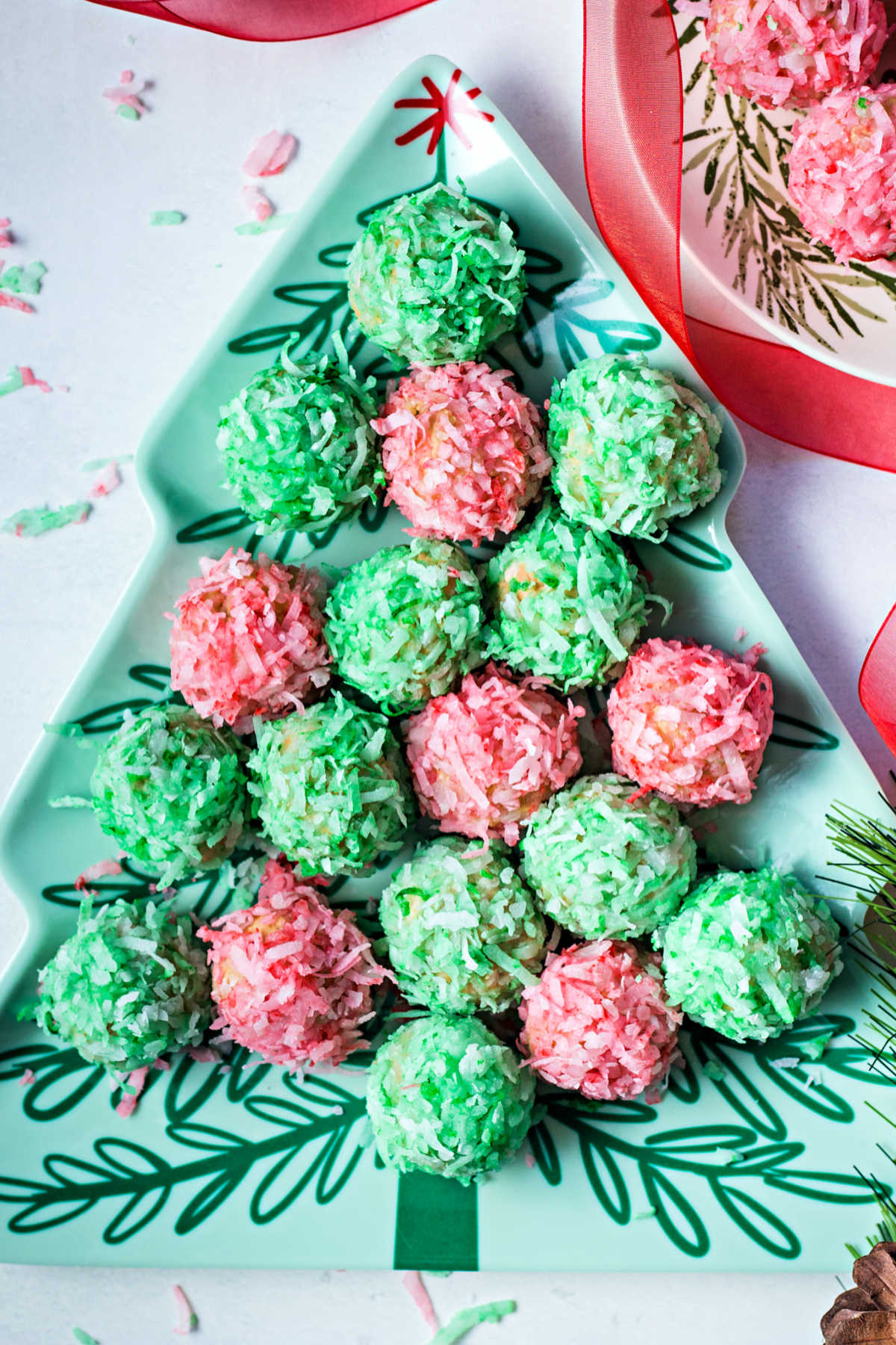 red and green coconut balls arranged on a tree shaped plate on a table.