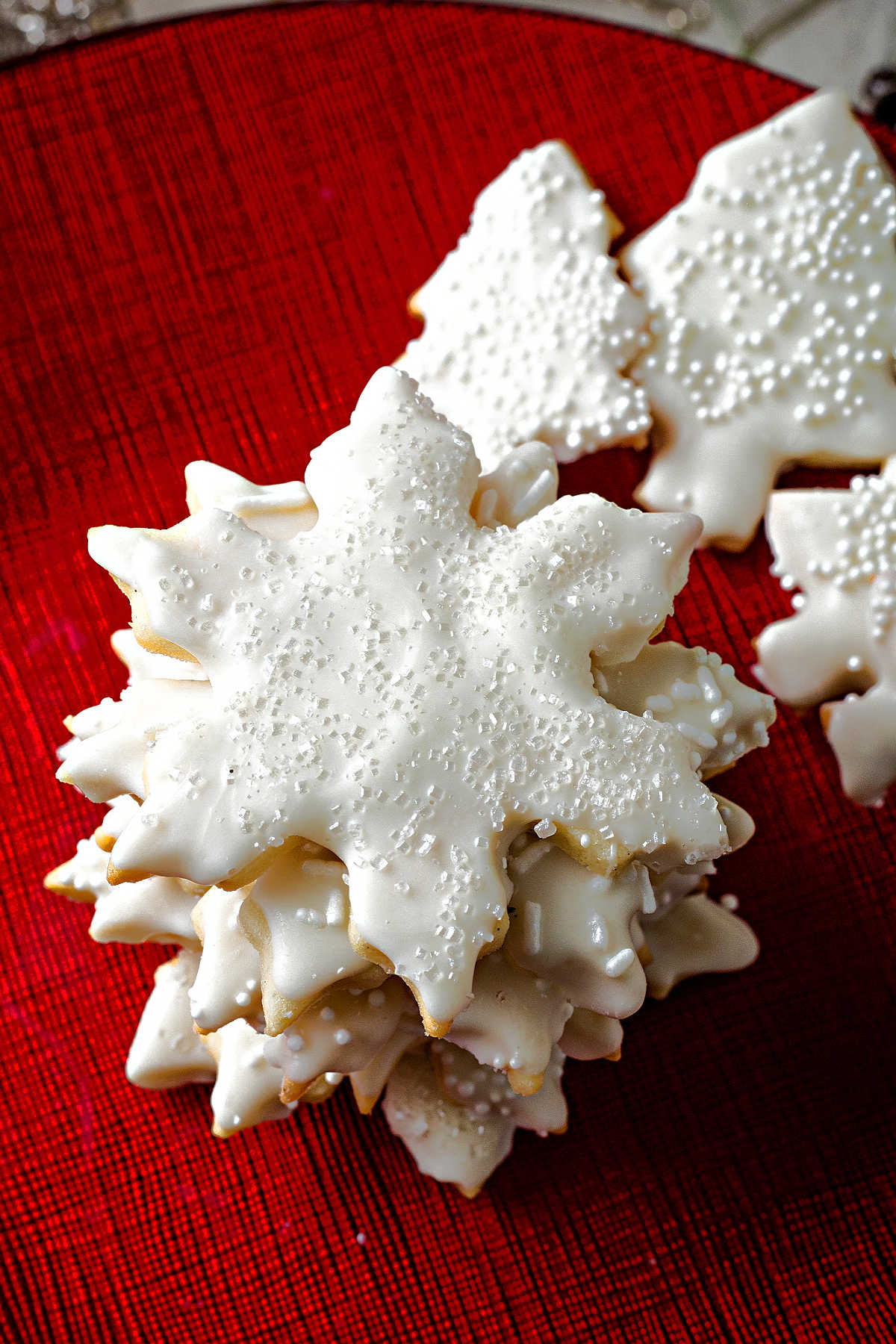 a stack of snowflake shaped vanilla cookies on a red plate.