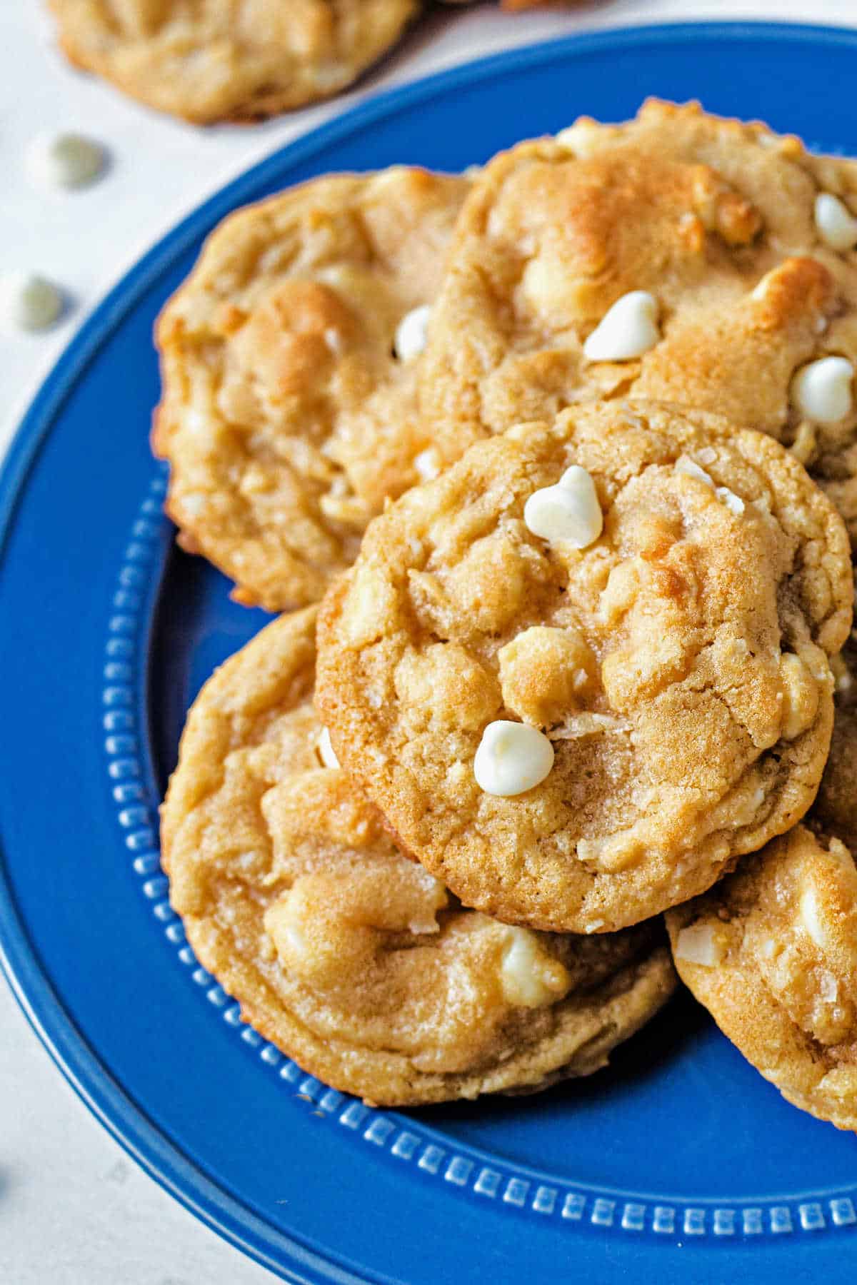 white chocolate macadamia nut cookies stacked on a blue plate on a table.