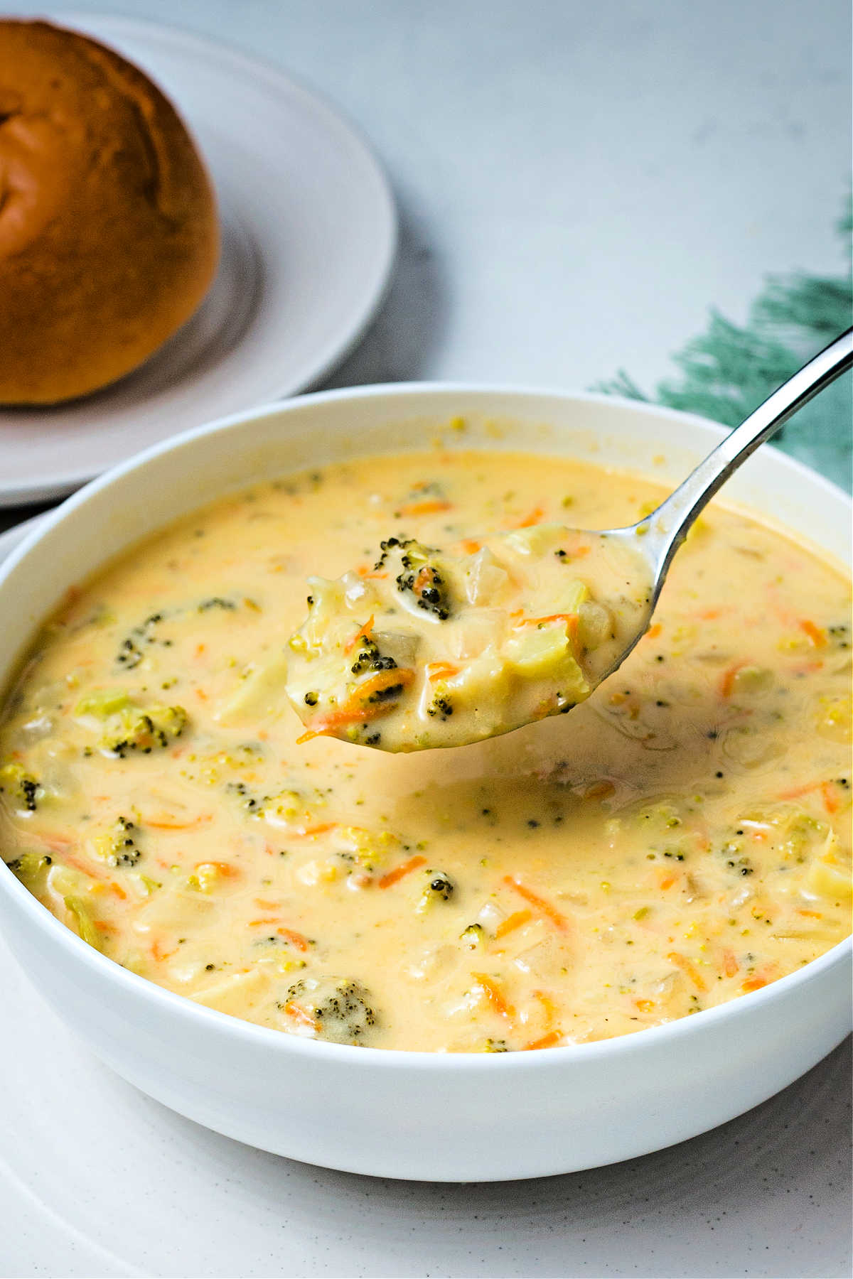 a spoonful of crockpot broccoli cheddar soup being lifted out of a bowl.