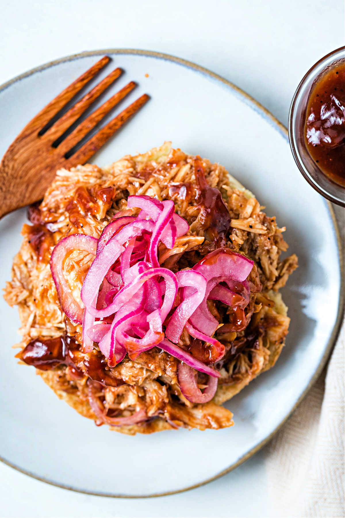 top down view of slow cooker pulled chicken open face on a bun on a plate.