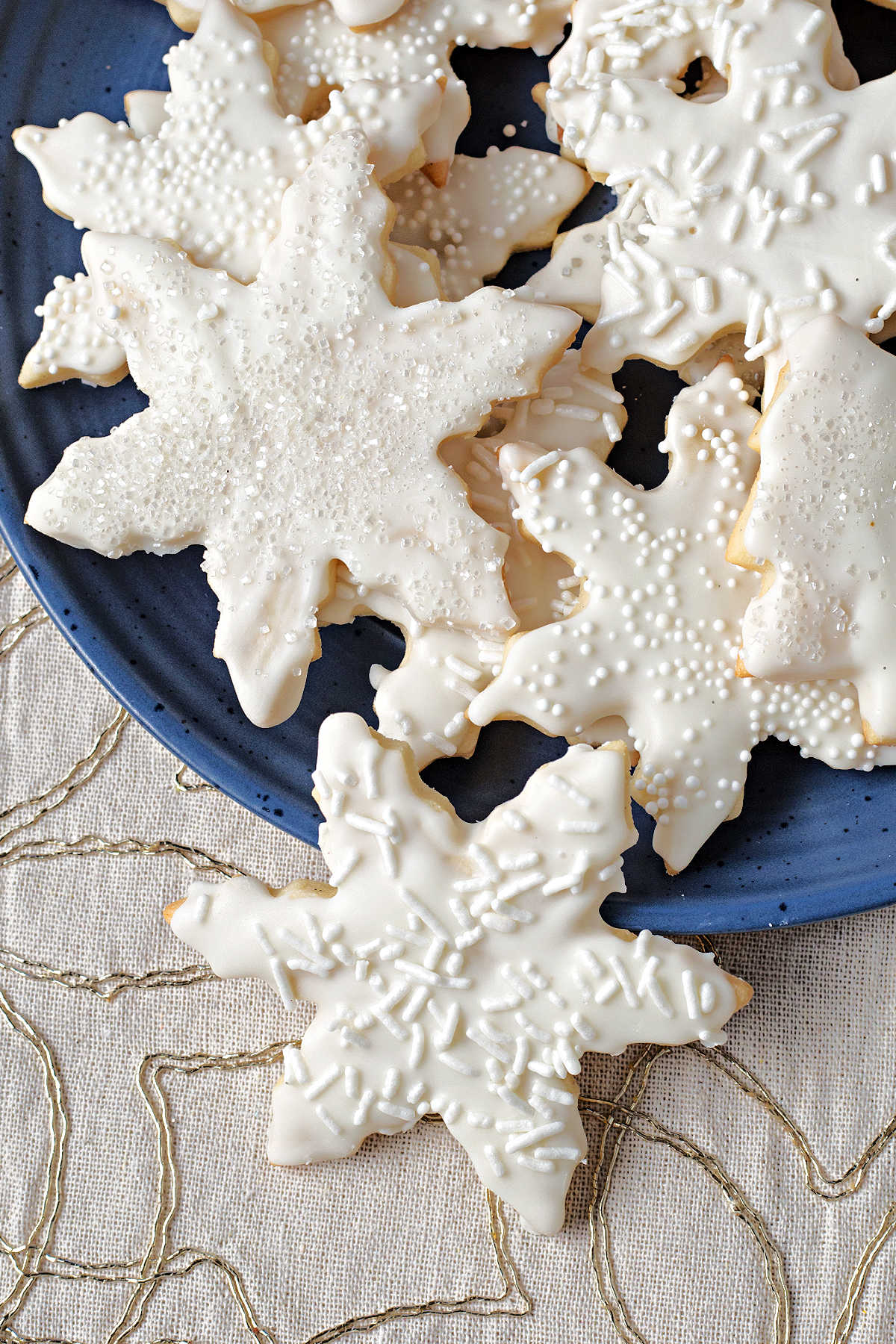vanilla cookies in star shapes cascading off a blue plate onto a table.