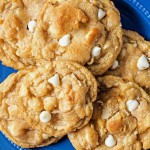 white chocolate macadamia nut cookies stacked on a blue plate on a table.