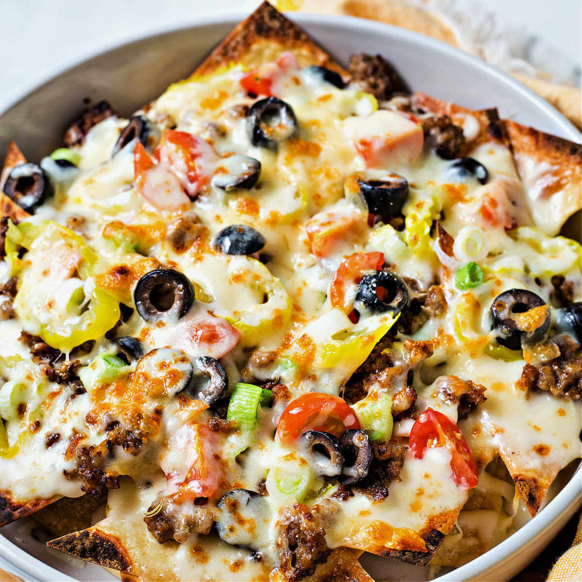 a pan of Italian nachos with melted mozzarella on top.