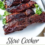 barbecue sauce slathered country style ribs on a white platter garnished with parsley.
