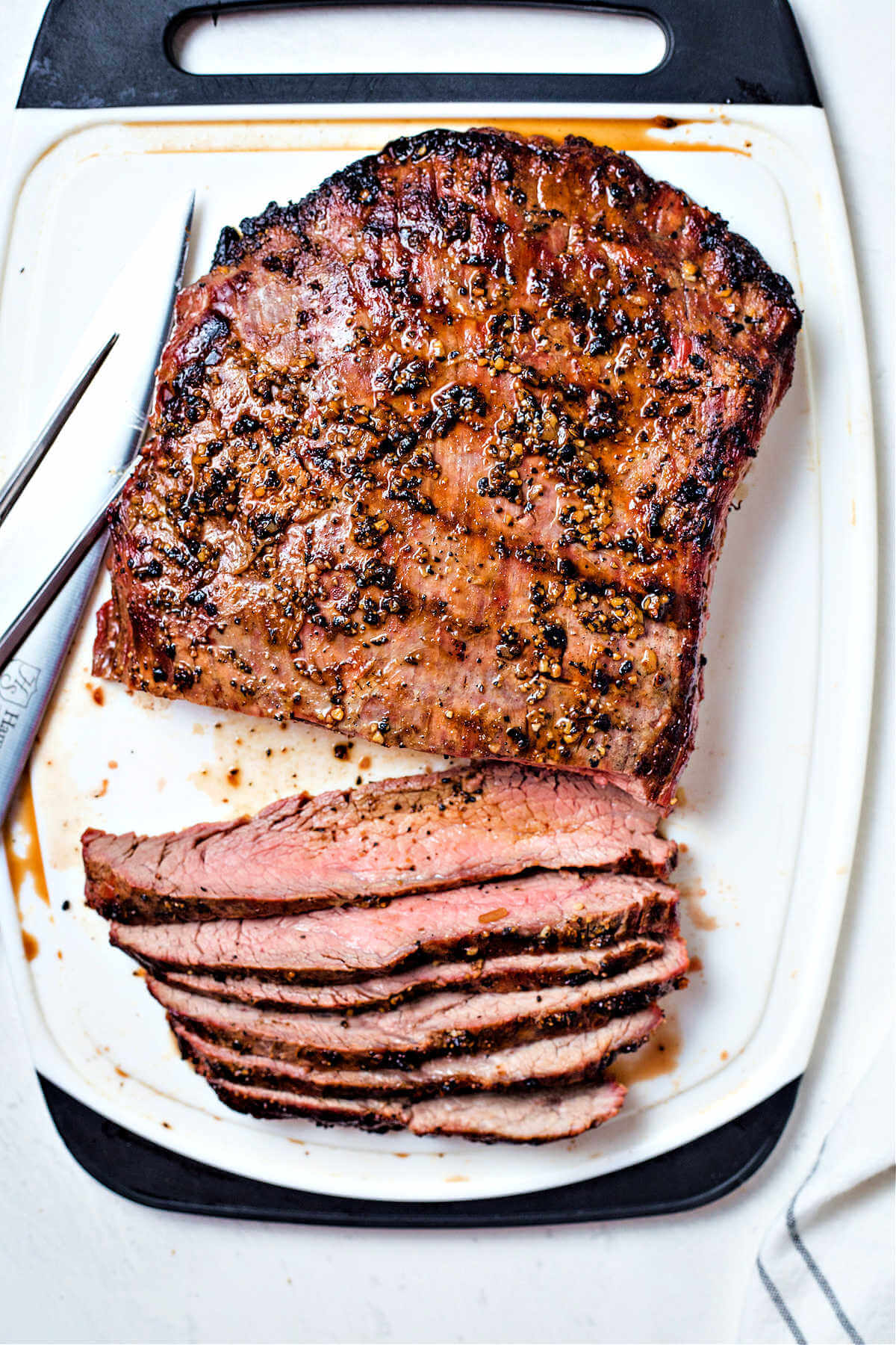 grilled flank steak on a cutting board with slices laying to the side.