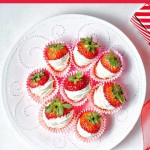 a plate of white chocolate dipped strawberries with red ribbon in the background.