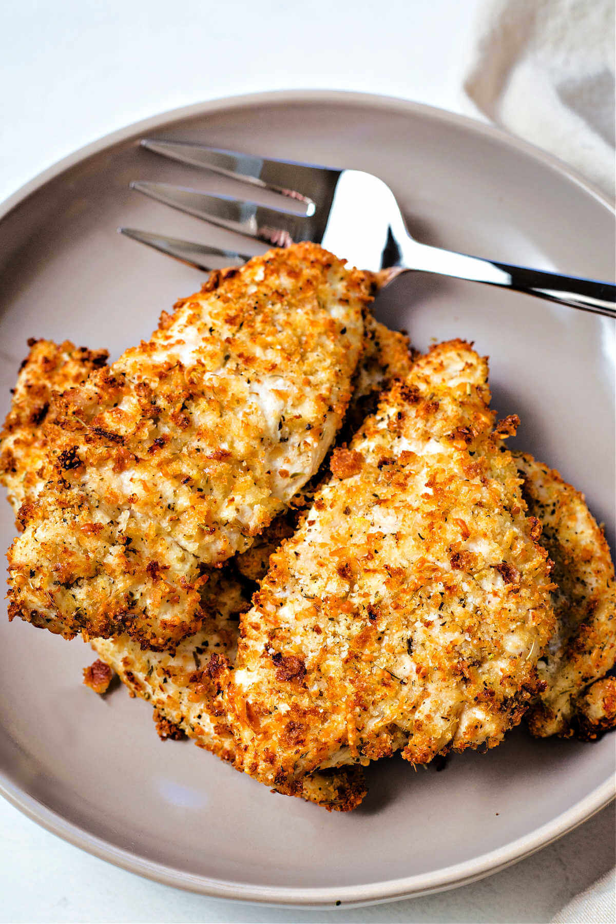 a plate of air fryer chicken cutlets with a meat fork.