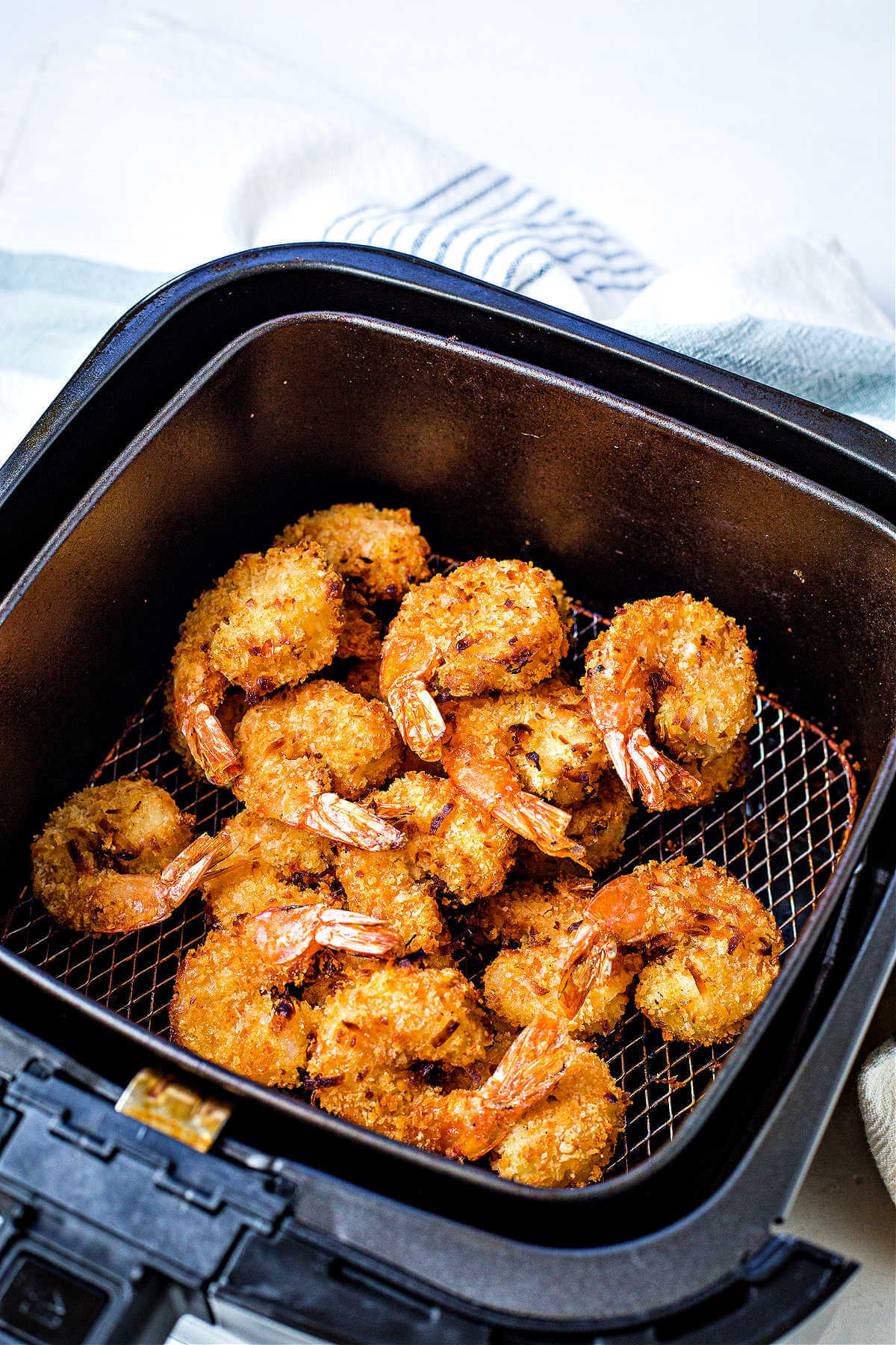 cooked air fryer coconut shrimp in an air fryer basket.