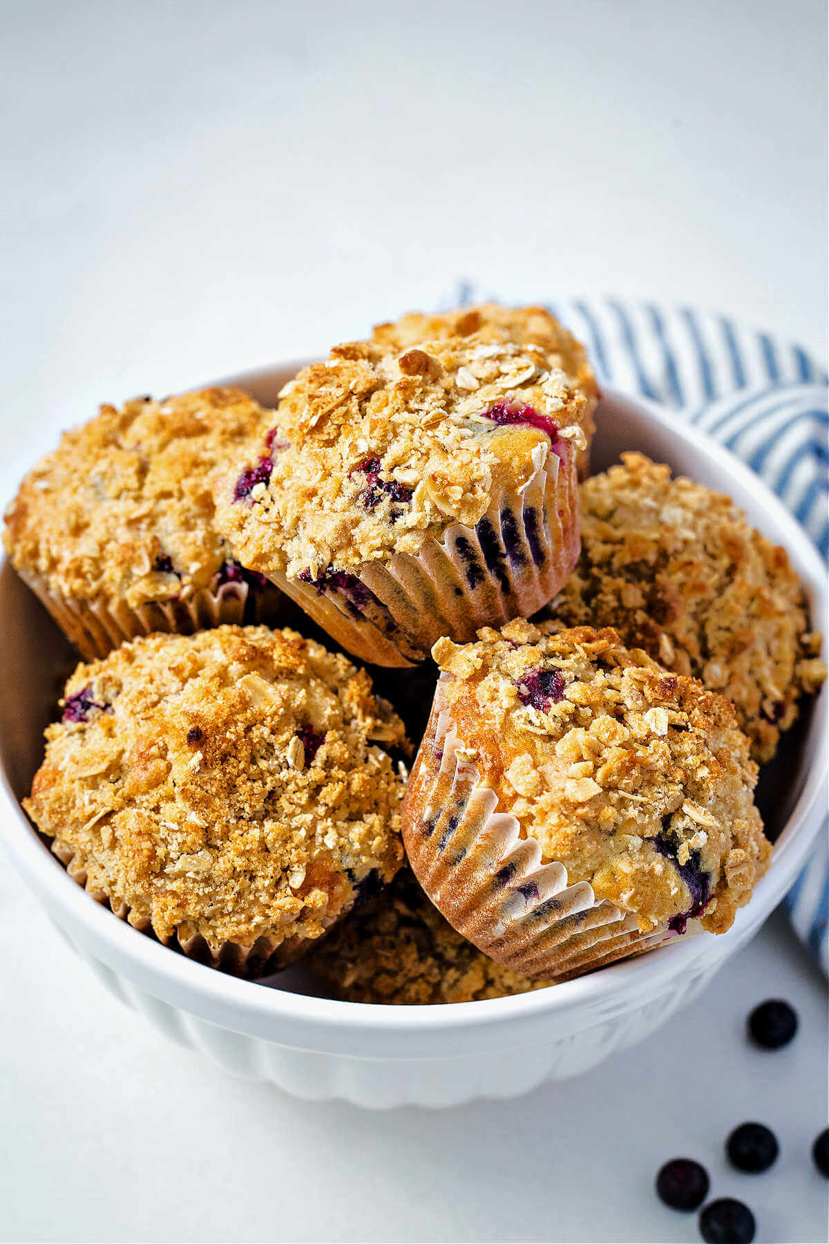 blueberry oatmeal muffins piled into a white bowl on a table.