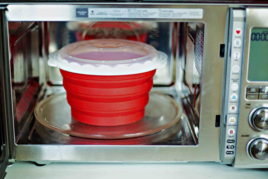 a silicone popcorn popper sitting inside an open microwave.