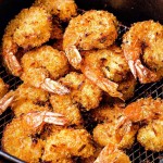 cooked air fryer coconut shrimp in an air fryer basket.