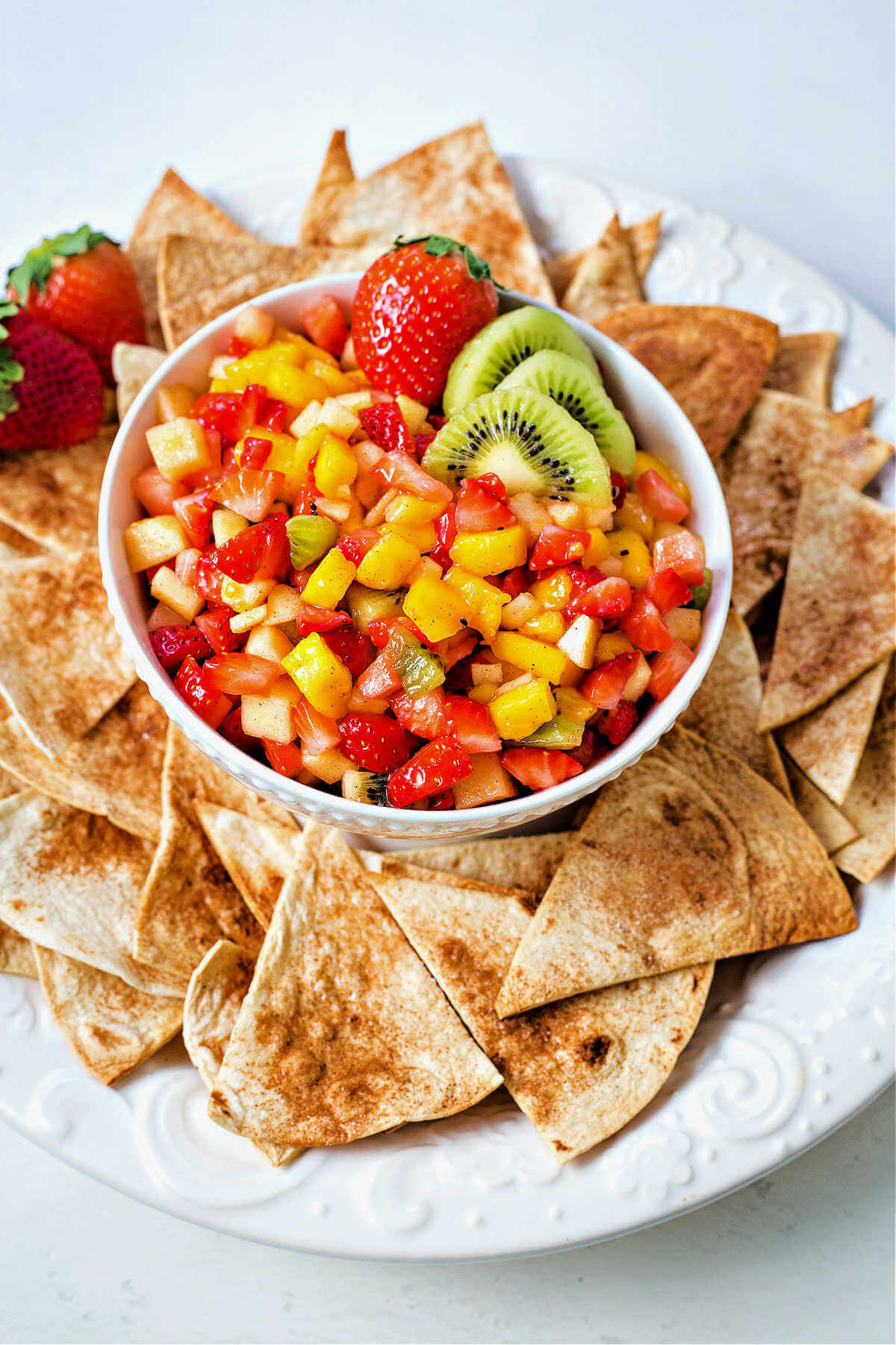 fruit salsa in a bowl with cinnamon tortilla chips surrounding it.